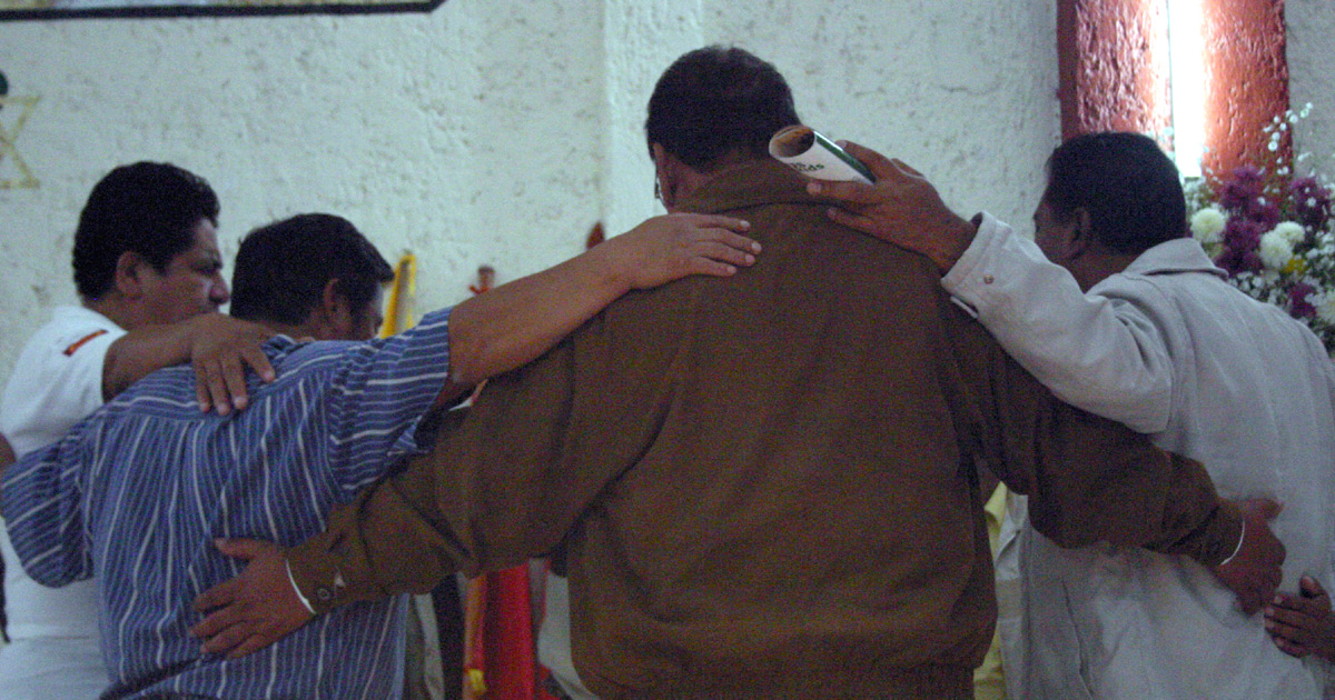 A group of men praying, arms wrapped around each other