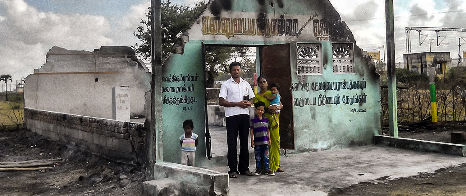 India - Family standing in front of burned out church - Photo: VOMC